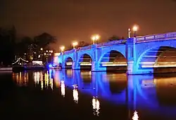 Picture of a road bridge across the river at night, illuminated with blue lights.