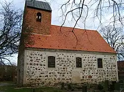 Stone building with three windows, red roof and brick bell tower