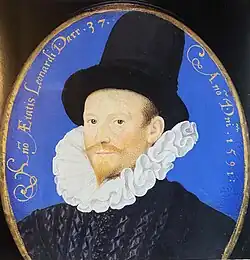 Leonard Darr wearing a black hat and sporting a Dutch ruff, or collar. He also wears a black quilted jacket with no obvious closure. The jacket has a sheen to it. Darr has a light, honey-red colored mustache and goatee. He has light hazel eyes and a symmetrical face. His skin is very white and his cheeks are rosy colored.