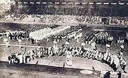 Black and white image of national teams marching into the stadium behind their national flag
