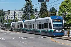 A four-car train on surface streets passing through an empty intersection