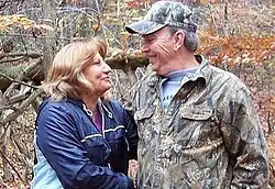 Lisa Guy (left) and Joel Guy looking at each other affectionately against a natural backdrop