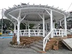 A gazebo that is coated in white paint and a woman sat inside.