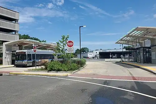 A silver bus at a bus station with angular concrete shelters