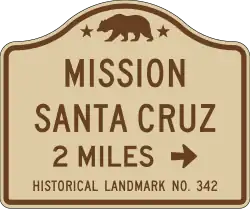 The California Manual on Uniform Traffic Control Devices specifies a standard road sign guiding motorists to California Historical Landmarks, such as Mission Santa Cruz.