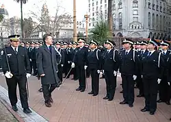 Macri, in an overcoat, walks down a line of young police officers