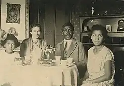 Mandenga and Emilie Diek with their daughters sitting at a table set with cups and flowers