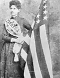 Mena E. Williams Hirshberg holding a US flag made from silk grown at The Grove, 1885