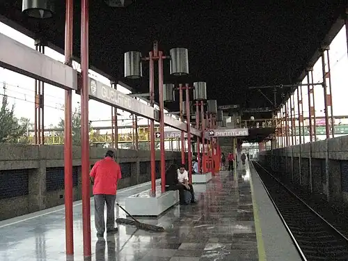 Many people are waiting seated on the station platform.