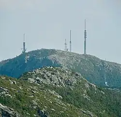A forested mountain dotted with four large steel transmission towers