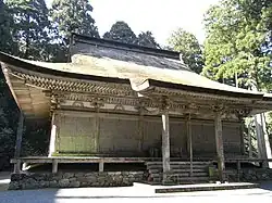 A wooden building with slightly raised floor, a hip-and-gable roof and a canopy over the steps.