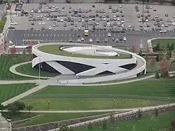 Aerial view of round white museum with grassy roof and grounds
