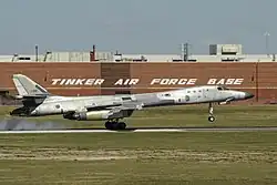 A mostly natural metal B-1B Lancer landing at the end of a post-maintenance check-flight at Tinker AFB during 2017. The large building behind forms part of the Oklahoma City Air Logistics Complex.