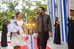 Bukele and his wife walking with their two daughters surrounded by soldiers