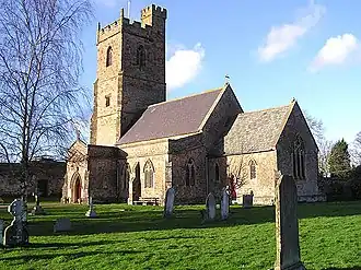 Stone building with prominent square tower. In the foreground are gravestones.