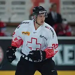 Hockey player dressed in a white jersey with a red cross as the logo
