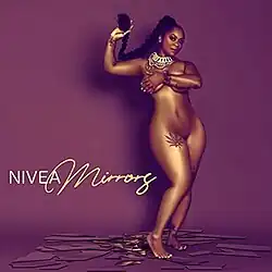 A nude woman standing on top of several mirrors while hiding her breasts and holding out her ponytail