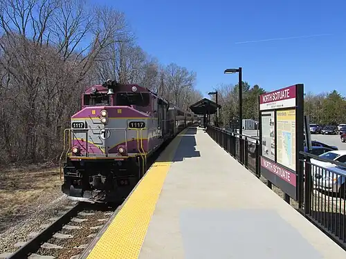 A diesel locomotive pulling a passenger train into a station with a high-level platform
