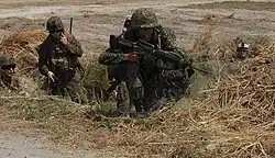 Philippine Marine Private Damaranan rushes up a small ditch to engage role-playing enemy forces while Staff Sgt. John Ross of 31st Marine Expeditionary Unit provides communication during amphibious landing training of Balikatan Exercise.