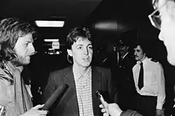 Paul McCartney being interviewed by two reporters holding microphones.