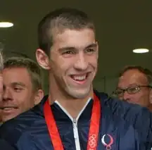 Michael Phelps smiling with an Olympic medal around his neck
