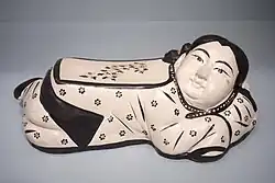 Headrest mould-formed as a girl, Jin dynasty, with overglaze enamels