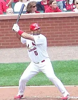 A man with feet spread apart holding a baseball bat in the air