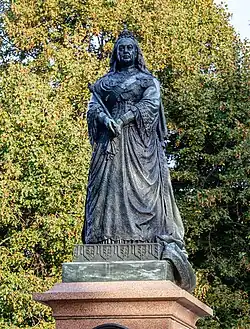 A statue of Queen Victoria on top of a plinth with trees in the background.