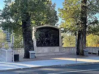 A photo of the Robert Gould Shaw Memorial taken after the completed renovations in 2021. The photo depicts the sculpture set further back from the street to allow for more standing room and benches.