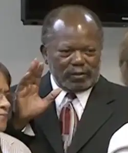 Afro-American male facing two people with right hand raised in swearing-in ceremony