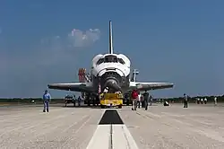 Atlantis being towed back with some workers in the front after its final landing