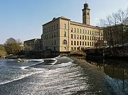 A large mill above a weir on a wide river