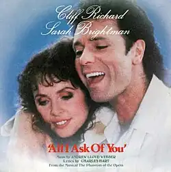 A photograph displaying Cliff Richard laying his right arm over the shoulder of Sarah Brightman.