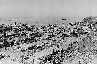 Shana Village in Etorofu (Shōwa period). There is a village hospital in the front, a factory in the left back with a fishery and a central radio tower (before 1945).