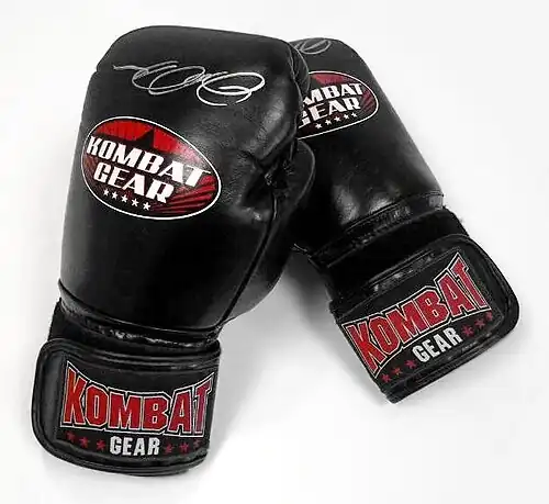 Photograph of a pair of black velcro sparring gloves, with Kombat Gear brand logos.