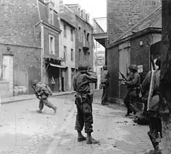 Black and white photograph of men wearing military uniforms in a town