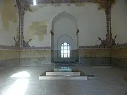 Photograph of the interior of a mausoleum showing a window and decorated tile on the walls