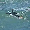 A surfer paddling.