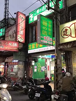 A street in Taipei with several signs in Chinese. One sign reads 二哥の店, lit. 'Second Brother's Shop', using の instead of 的.