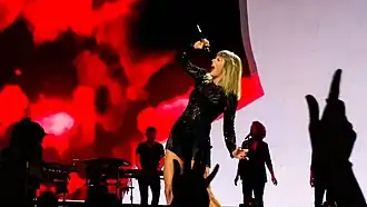 Swift singing on a mic dressed in a black dress
