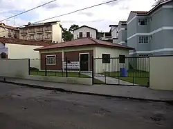 A small lot with a garden surrounded by walls and a gate with the Kingdom Hall in its center