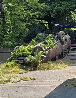 Film set of broken cars with growing foliage