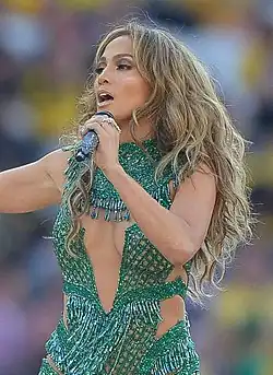 Jennifer Lopez singing on stage in a green outfit