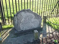 Stone monument in front of a metal fence