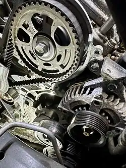 Photo depicting a rubber timing belt with incrementally spaced rubber teeth designed to align with the splines or grooves of crankshaft and camshaft pulleys.