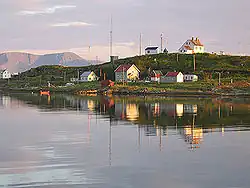 The Torsvåg lighthouse sits at the top of Kåja. The largest house is the Figenschow building, and the house on the far left is the Solberg building. Behind Kåja we can see Nordkvaløya.
