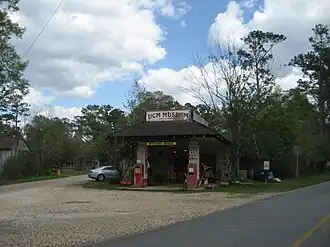Colorful front facade of the Abita Mystery House with gas pumps and folk art displays