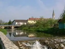 A view of the bridge crossing the river and the church tower, visible at the bottom right