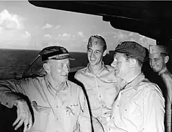 Black and white photograph of four men in khakis on a ship at sea