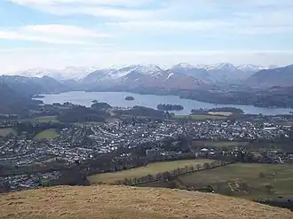 View of lake surrounded by mountains, seen from a mountain peak